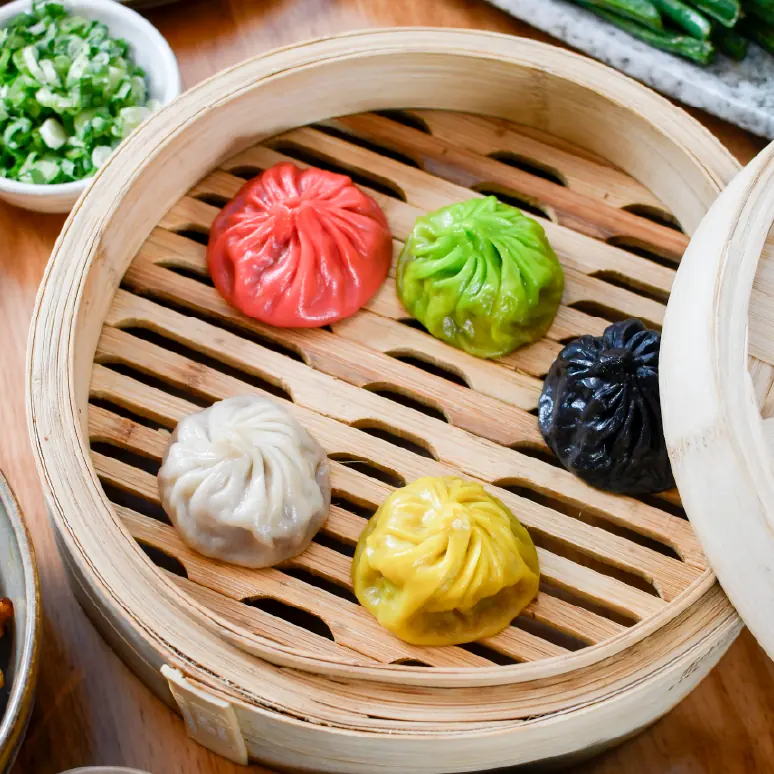 Rainbow soup dumplings in a bamboo steamer